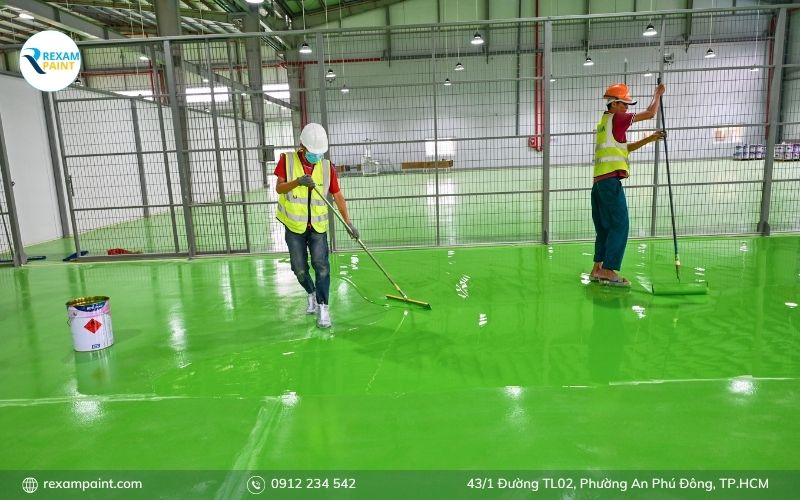 Thợ thi công đổ và gạt lớp sơn epoxy tự phẳng, dùng lăn gai phá bọt khí