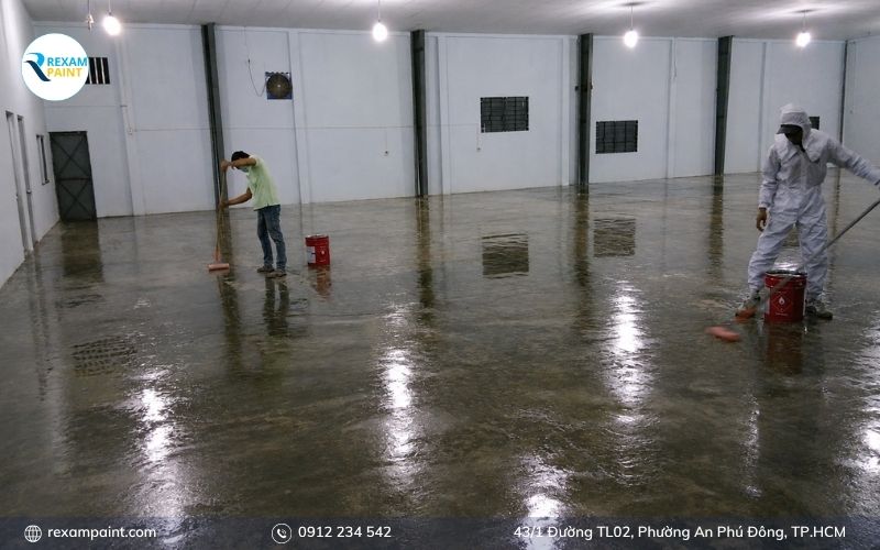 Nhân viên lau bảo dưỡng sàn epoxy trắng trong khu vực sản xuất