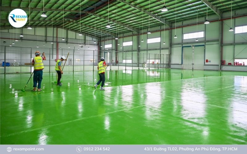 Nhiều thợ thi công sơn epoxy song song trên sàn nhà xưởng diện tích lớn với bộ dụng cụ đầy đủ