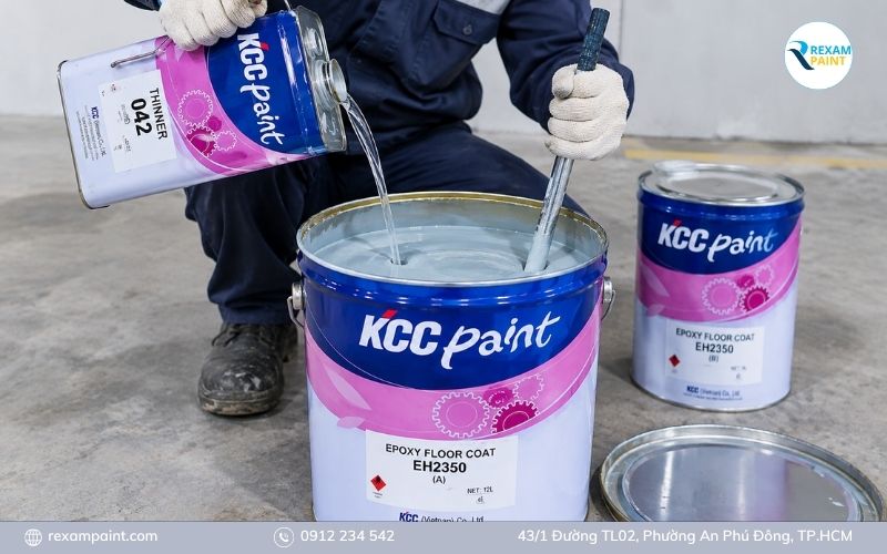 Thợ đang đong dung môi và khuấy đều thùng sơn epoxy hai thành phần