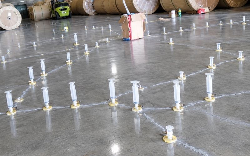 Thợ thi công bơm keo epoxy chống thấm vào rãnh chữ V trên sàn bê tông theo từng bước